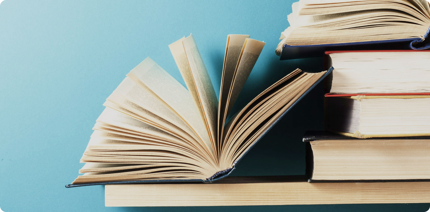 책들이 쌓여있고, 두권의 책이 펼쳐지고 있는 모습